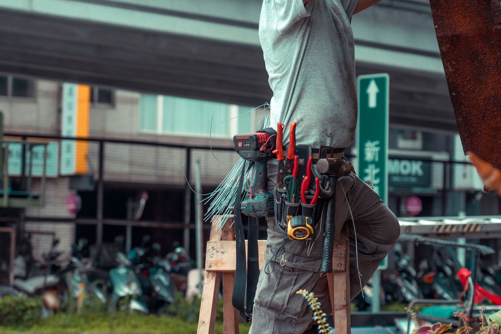 A maintenance technician on a ladder with a full tool belt